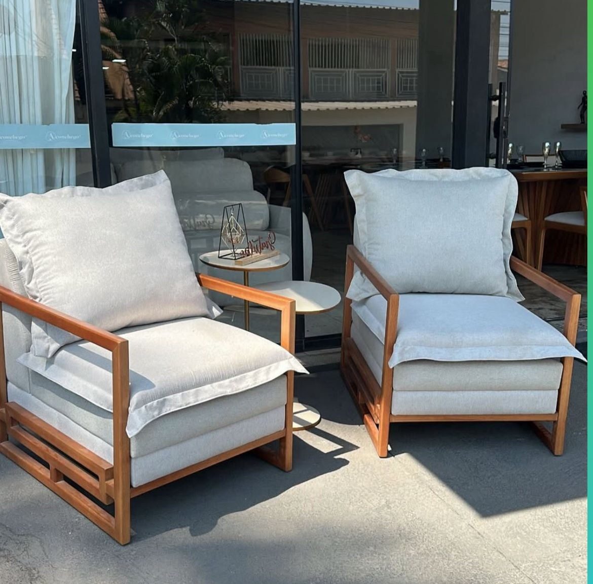 Poltronas de madeira com almofadas cinza em frente ao showroom